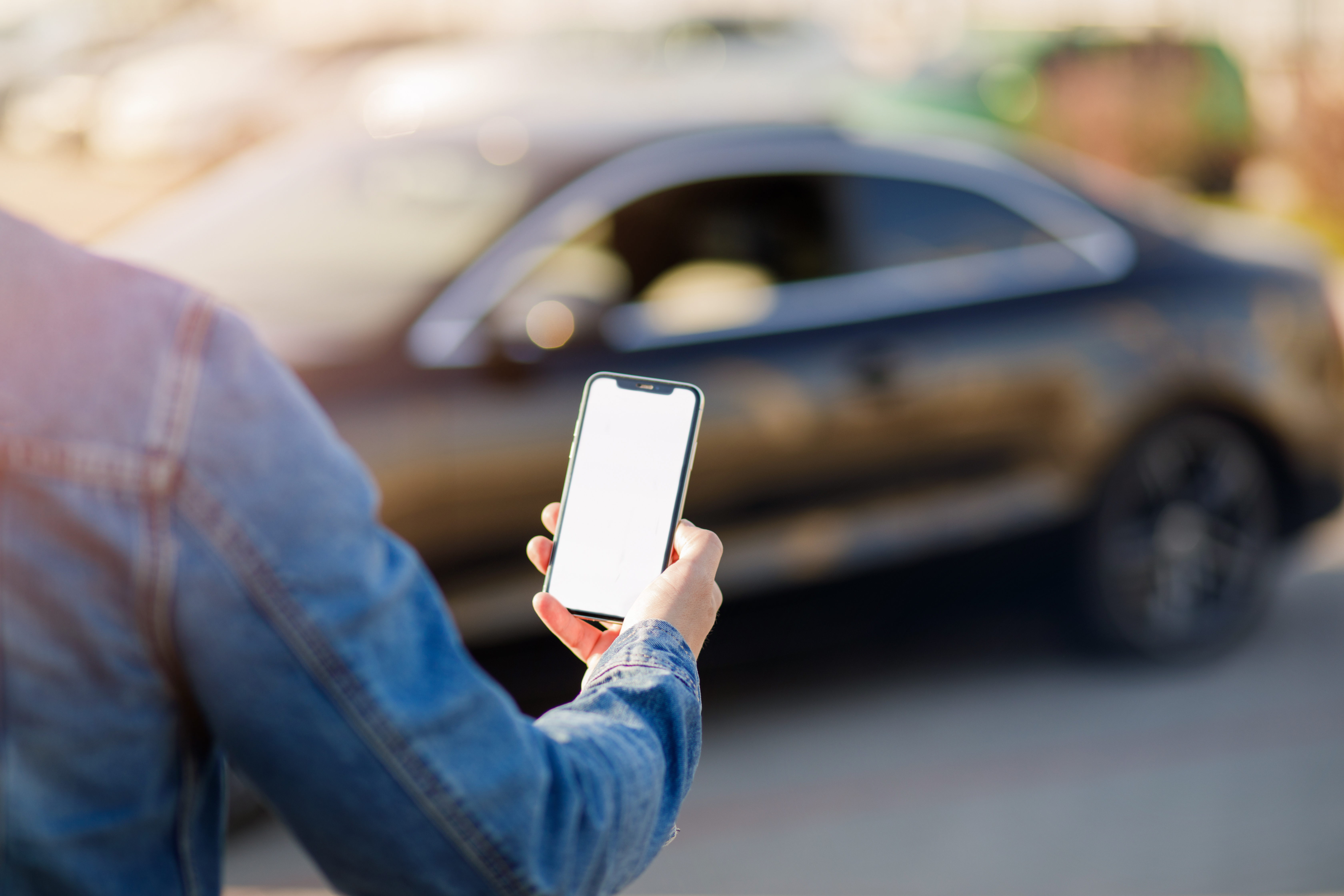 Person holding smartphone with car in background representing ride-hailing and delivery app opportunities in South Africa