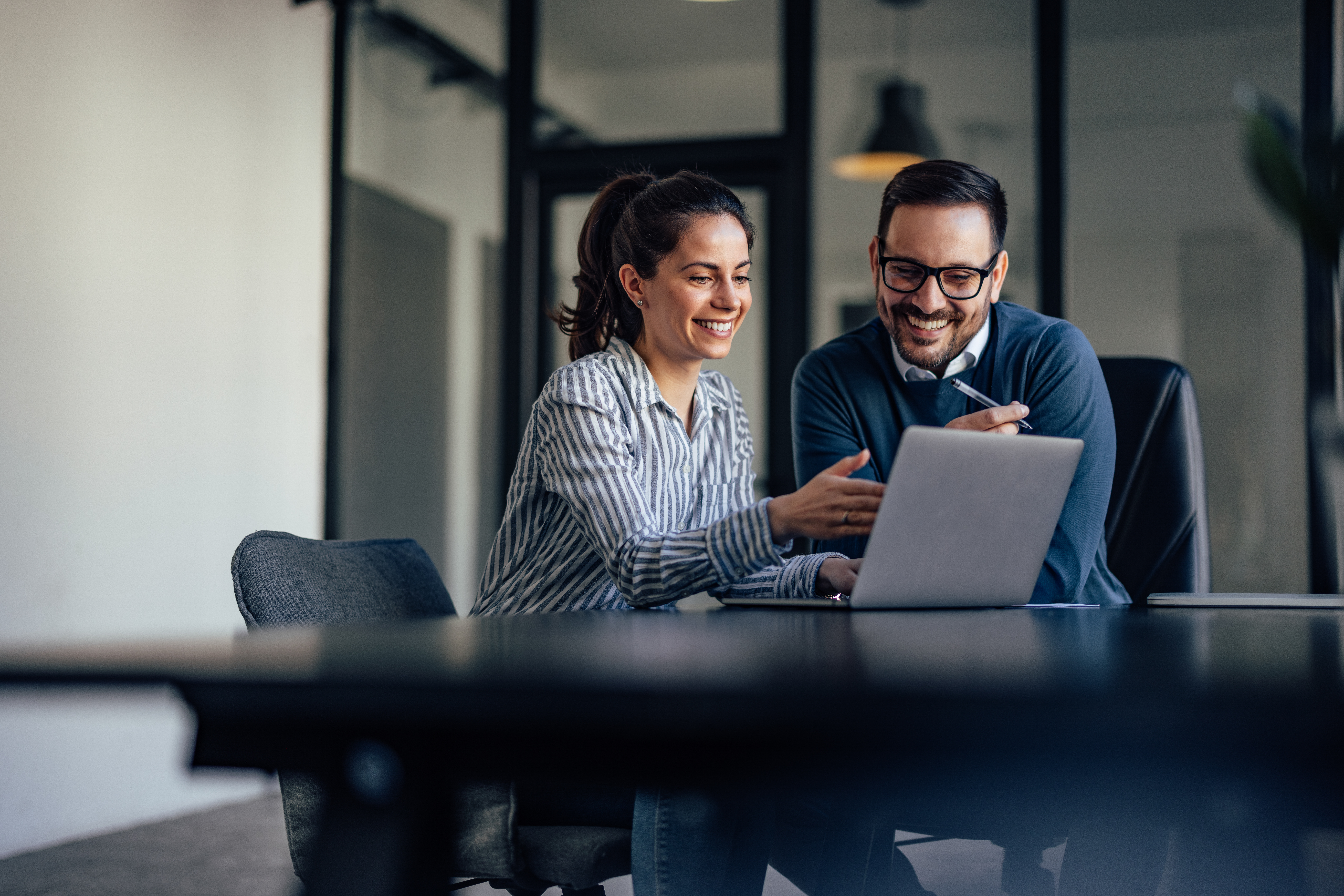 Happy business owners discussing Business Insurance protection while working together on computer