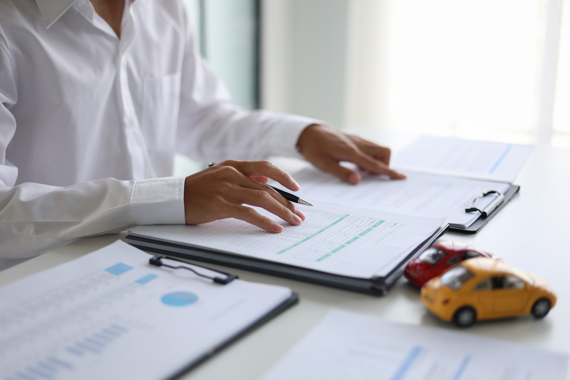Insurance consultant reviewing car insurance documents in South Africa with toy cars on a desk