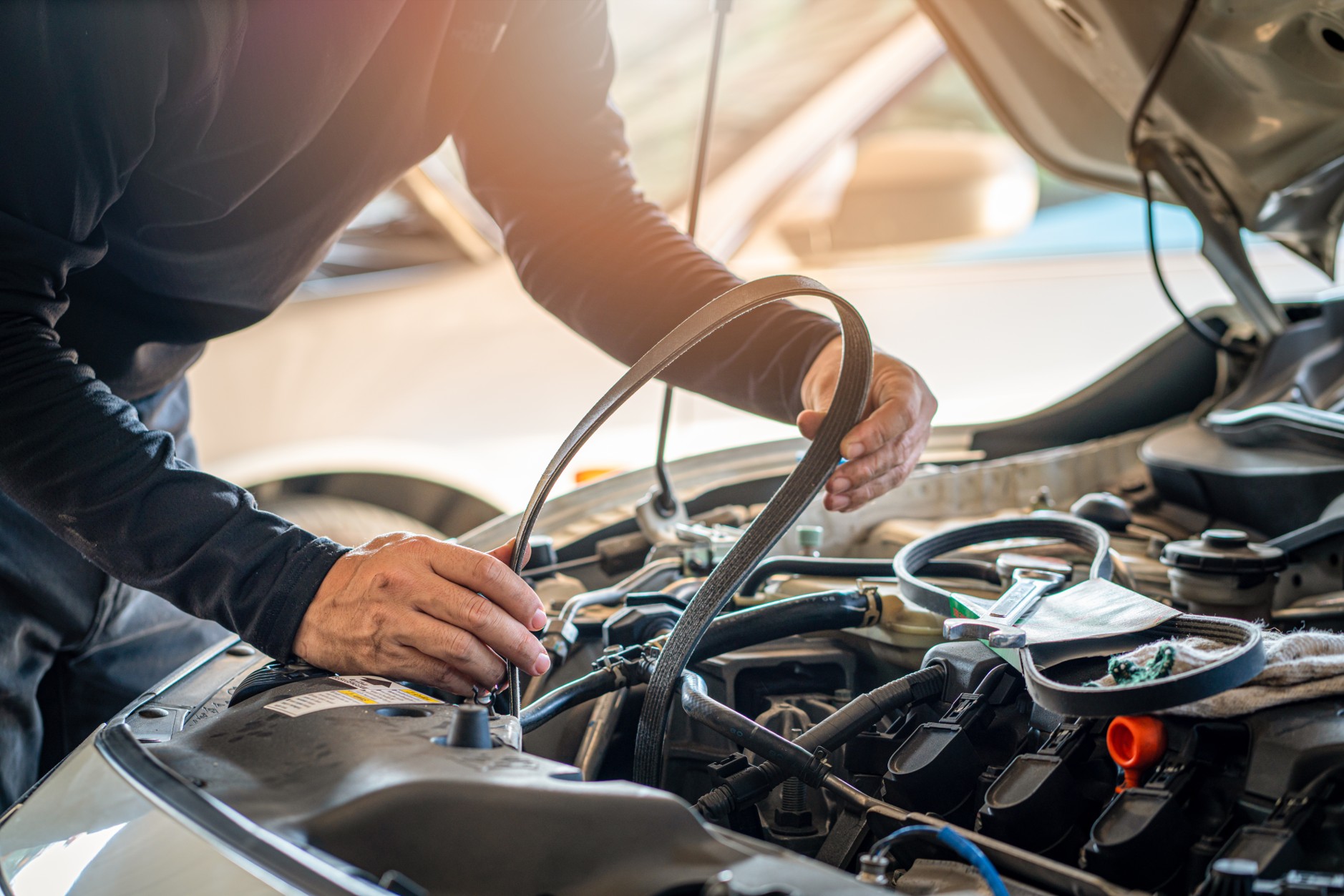 Mechanic inspecting a car engine and drive belt, representing motor warranty protection in South Africa