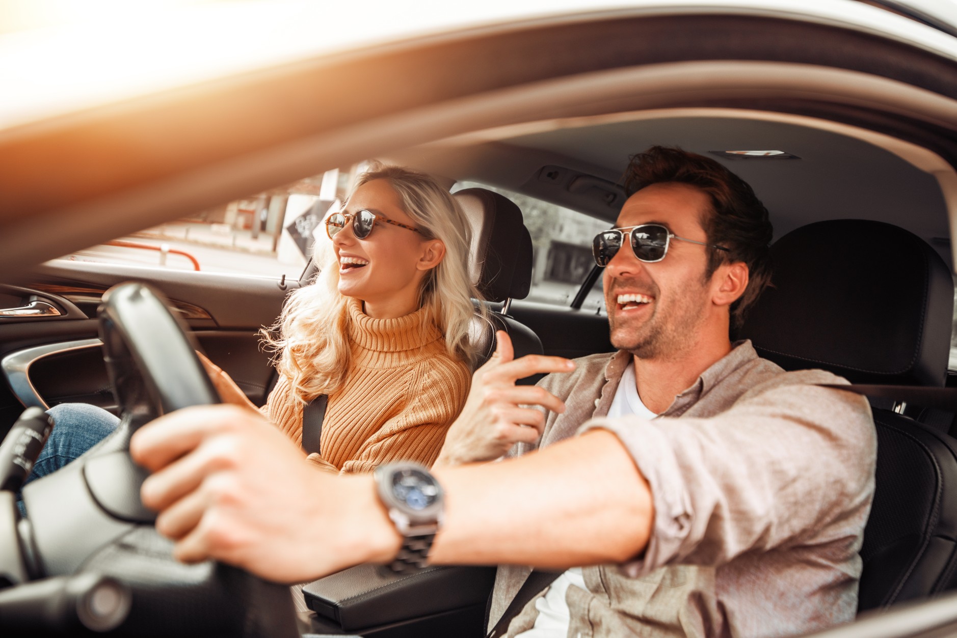 A happy couple smiling while test driving a used car in South Africa, highlighting the importance of inspecting a vehicle before signing a voetstoots agreement