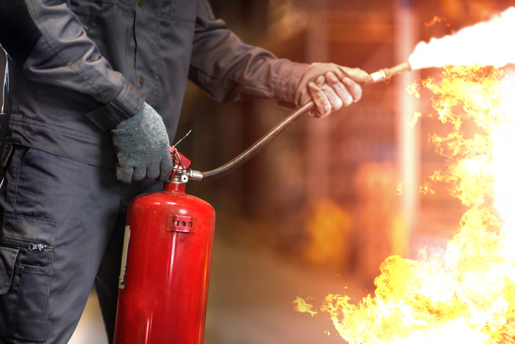 Person holding red fire extinguisher, illustrating fire insurance protection in South African