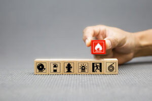 red cube with fire icon above wooden blocks showing various insurance symbols, emphasizing fire insurance concept