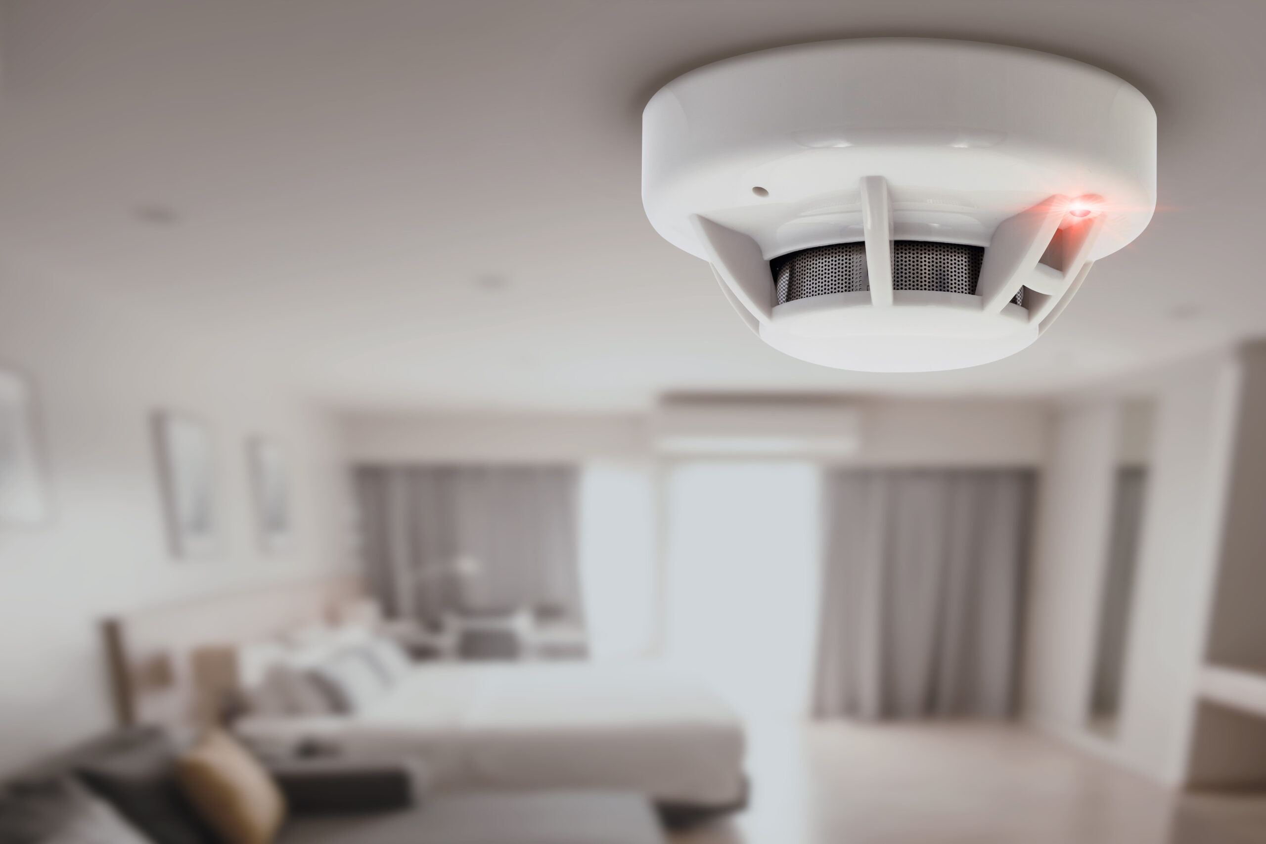 smoke detector with red led light mounted on ceiling, highlighting fire safety for insurance purposes